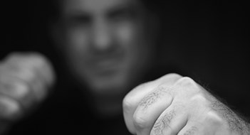 Q&A: Dangerous Mitchell-Lama Resident Portrait of abusive aggressive man punching fists from the darkness.
