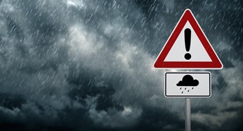 A dark cloudy sky with rain and warning sign - computer generated image
