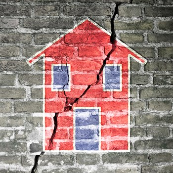 Cracked brick wall with a red house drawn on it -concept image