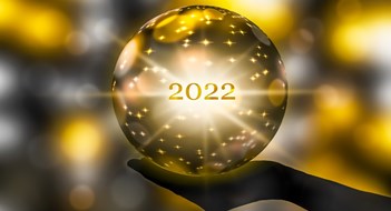 golden crystal ball in a hand, prediction for 2022, brights stars and sparks on abstract shiny background