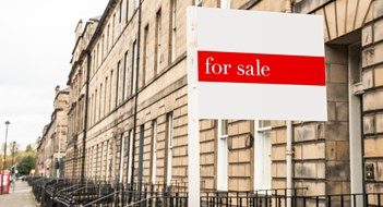 For sale sign in front of an old stone terraced house in a city centre on a cloudy autumn day. Edinburgh, Scotland, UK.