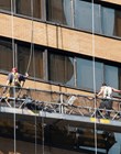 New York, New York, USA - August 5, 2010: Two men washing windows on a skyscraper. Working platform is raised and lowered by ropes.