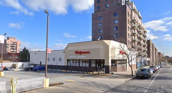 A parking lot, Walgreens pharmacy store, and mid-rise apartment building in Woodside, Queens, New York