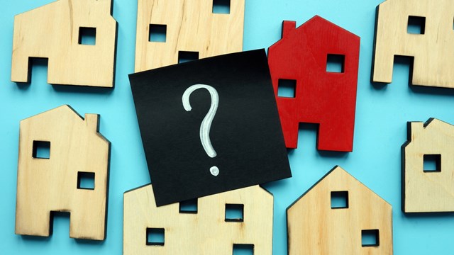 Tiny wooden houses and question mark. Home valuation and selection.