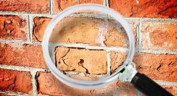 Façade Problems & SWARMP Certification Old italian brick wall with damaged bricks - Concept image seen through a magnifying glass.