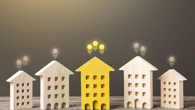 Five small wooden buildings with coins floating away from rooftops