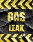 'GAS LEAK' warning sign in yellow block lettering on cracked black background 