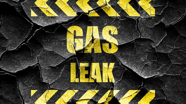 'GAS LEAK' warning sign in yellow block lettering on cracked black background 