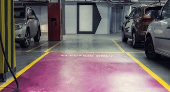 Electric car charging station in underground indoor parking with signage reading CHARGE STATION