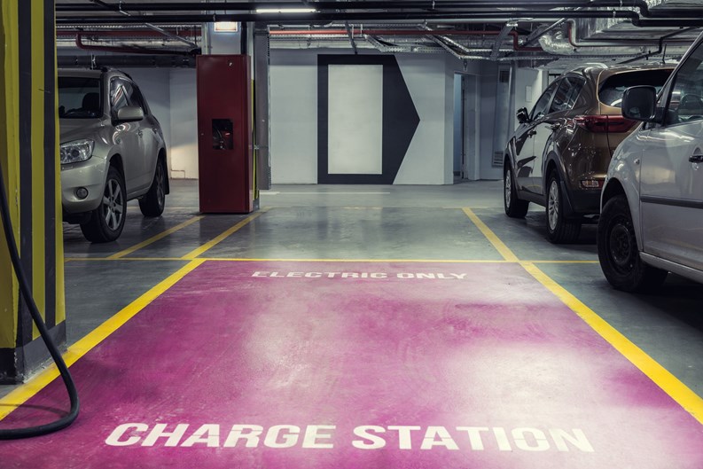 Electric car charging station in underground indoor parking with signage reading CHARGE STATION