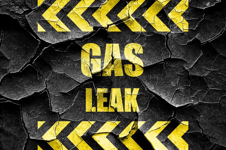 Gas Leak warning sign in yellow block letters on cracked black background 