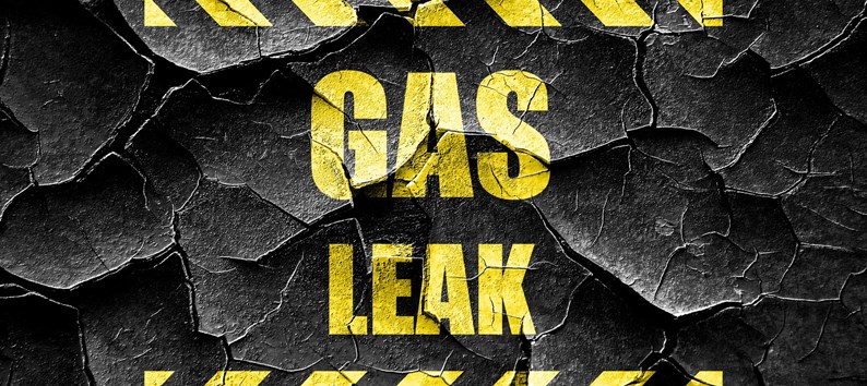 Gas Leak warning sign in yellow block letters on cracked black background 