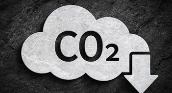 Cloud and co2 symbol with down arrow for greenhouse gas pollution reduction symbol on dark stone wall background