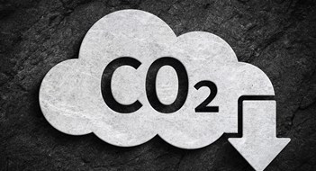 Local Law 97 Rules Unveiled Cloud and co2 symbol with down arrow for greenhouse gas pollution reduction symbol on dark stone wall background