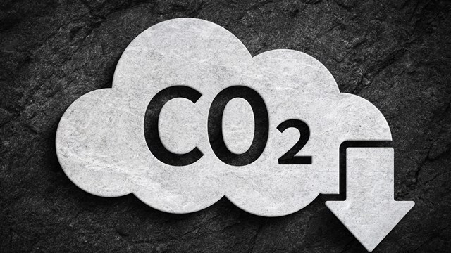 Cloud and co2 symbol with down arrow for greenhouse gas pollution reduction symbol on dark stone wall background