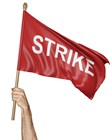 A man raising a red flag high in the air with the word strike on it.