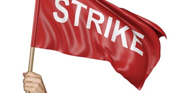 A man raising a red flag high in the air with the word strike on it.
