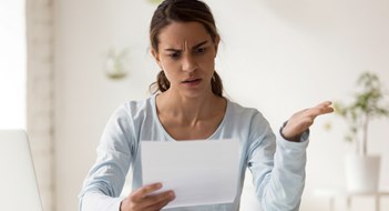 Head shot portrait stressed millennial mixed race woman reading paper with bad news. Frowning female employee irritated by dismissal notice. Unhappy young lady disagree with false information.