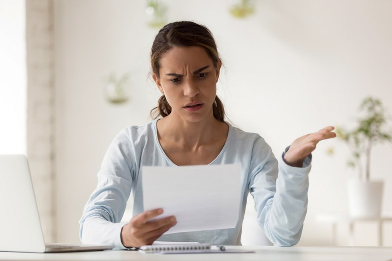 Head shot portrait stressed millennial mixed race woman reading paper with bad news. Frowning female employee irritated by dismissal notice. Unhappy young lady disagree with false information.
