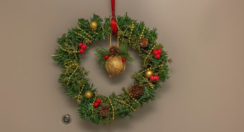 Holiday Display Rules Close up view of Christmas wreath of spruce branches hanging on apartment front door.