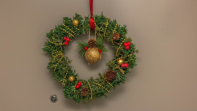 Close up view of Christmas wreath of spruce branches hanging on apartment front door.