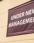 under new management sign banner on wall ouside shop in england.