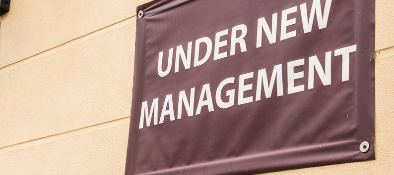 under new management sign banner on wall ouside shop in england.