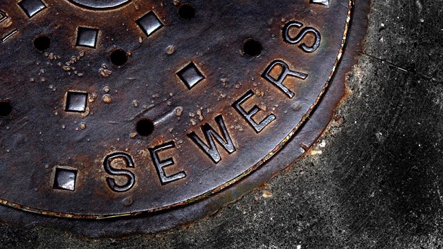 Man hole cover for sewer entry with iron grate on street in a city