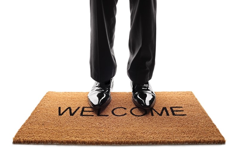 Pair of legs standing on a doormat with the word welcome written on it isolated on white background