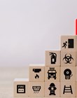 A graduated stack of wooden blocks showing different safety-related icons with a red block reading SAFETY at the top 