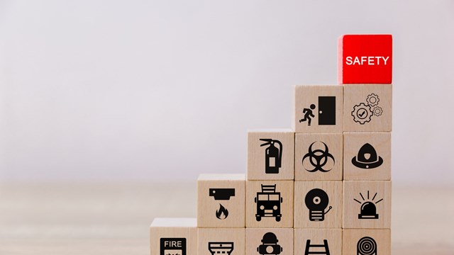 A graduated stack of wooden blocks showing different safety-related icons with a red block reading SAFETY at the top 