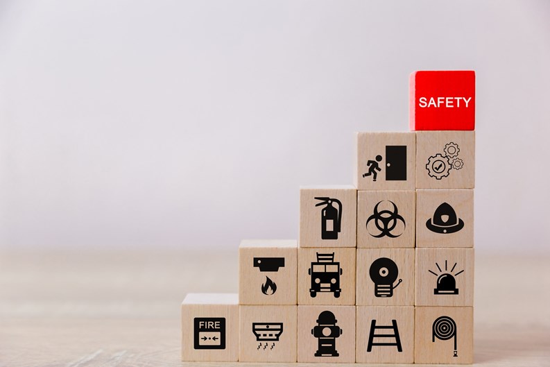 A graduated stack of wooden blocks showing different safety-related icons with a red block reading SAFETY at the top 