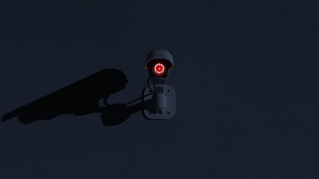 Surveillance camera glowing in the dark. Ominous mood scene with negative space. Digital 3D rendering.