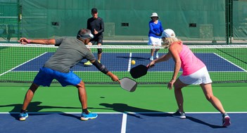 colorful action image of two couples playing pickleball in a mixed doubles match