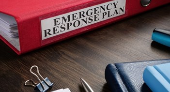 A Red folder with Emergency response plan on the desk.