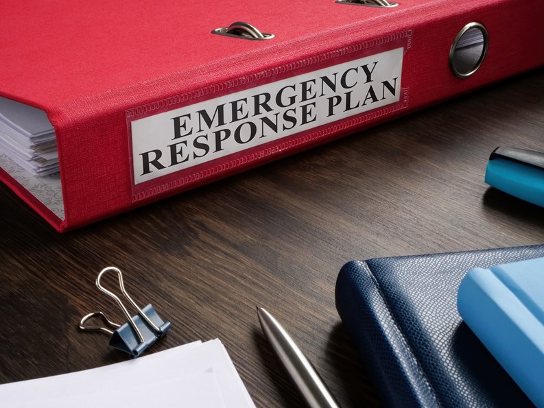 A Red folder with Emergency response plan on the desk.