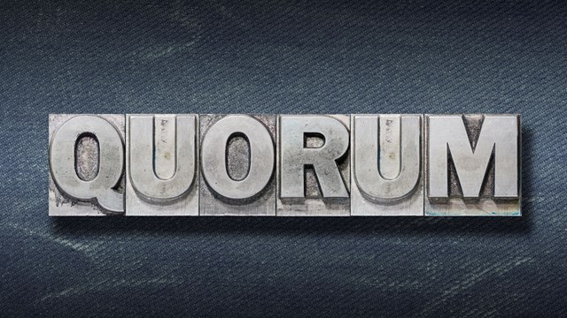 quorum word made from metallic letterpress on dark jeans background"r"n
