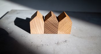 Group of similar wooden tiny toy houses. Wooden models of buildings as conceptual images for real estate topics.