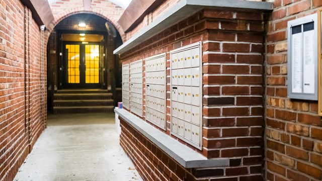Brick apartment building entrance in downtown NYC New York City with mailbox post mail boxes, empty corridor in evening night with nobody, secured area