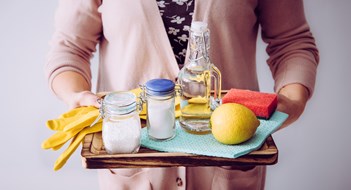 Understanding Green Cleaning Effectiveness, Sustainability, & Best Practices Natural cleaners concept. Woman holding eco friendly home cleaning ingredients, white vinegar, lemon, baking soda, citric acid concept.