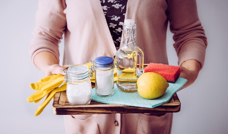 Natural cleaners concept. Woman holding eco friendly home cleaning ingredients, white vinegar, lemon, baking soda, citric acid concept.