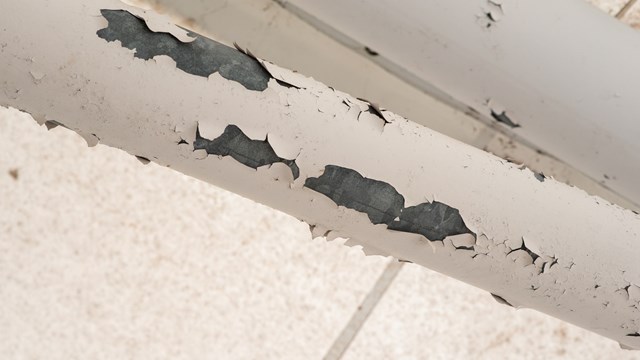 Photography of chiping lead paint on a pipe.