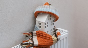 Essential Pre-Winter Maintenance Figure of house and warm clothes on heating radiator. Home heating expenses and savings concept.