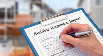 Exterior Safety Inspections Buiding Inspector completing an inspection form on clipboard beside new build construction
