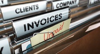 The Collections Process Close up on a file tab with the word invoice and a note where it is handwritten unpaid with blur effect. Concept image for illustration of unpaid invoices recovery.