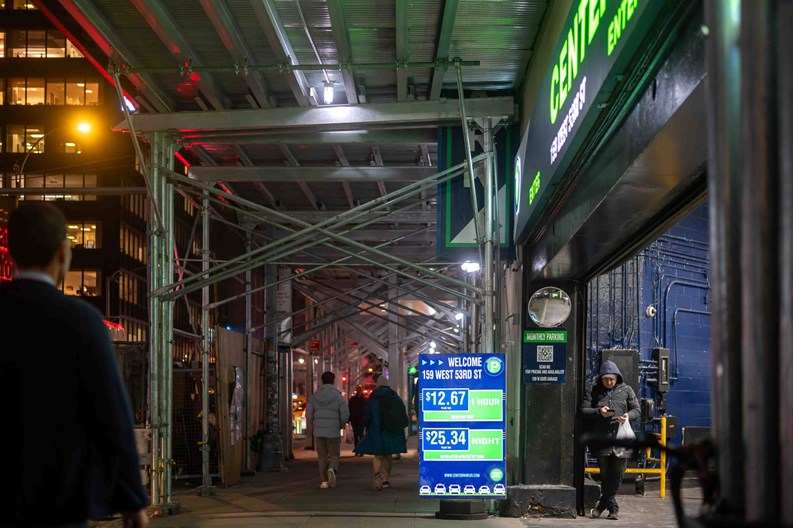 New York, NY, USA, 12-05-2023 New York City night time street scene with scaffolding parking garage entrance and pedestrians. Editorial use only.
