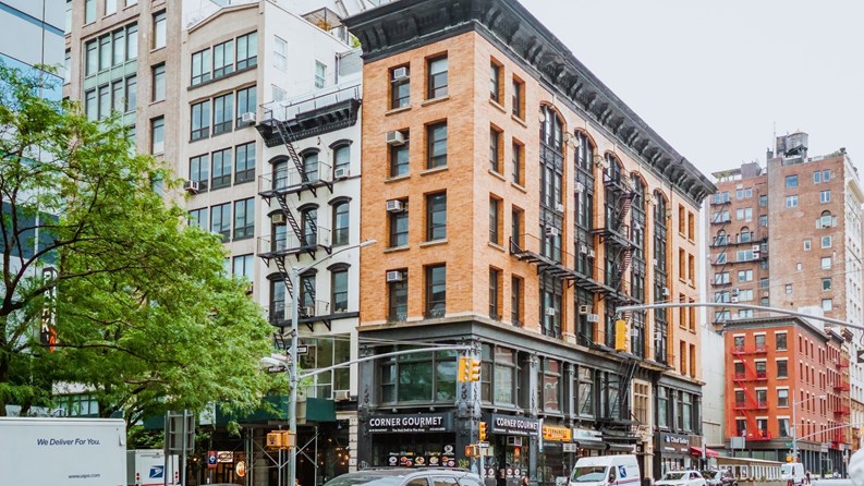 New York City Street View of Residential Buildings and Passing Cars