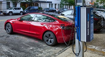 E-Device Charging Stations New York, NY - August 24, 2021: Recharging an electric car at a curbside NYC electric vehicle charger in the Upper East Side of NYC. This charger is provided by Flo in partnership with Con Edison and NYC DOT, (Department of Transportation)
