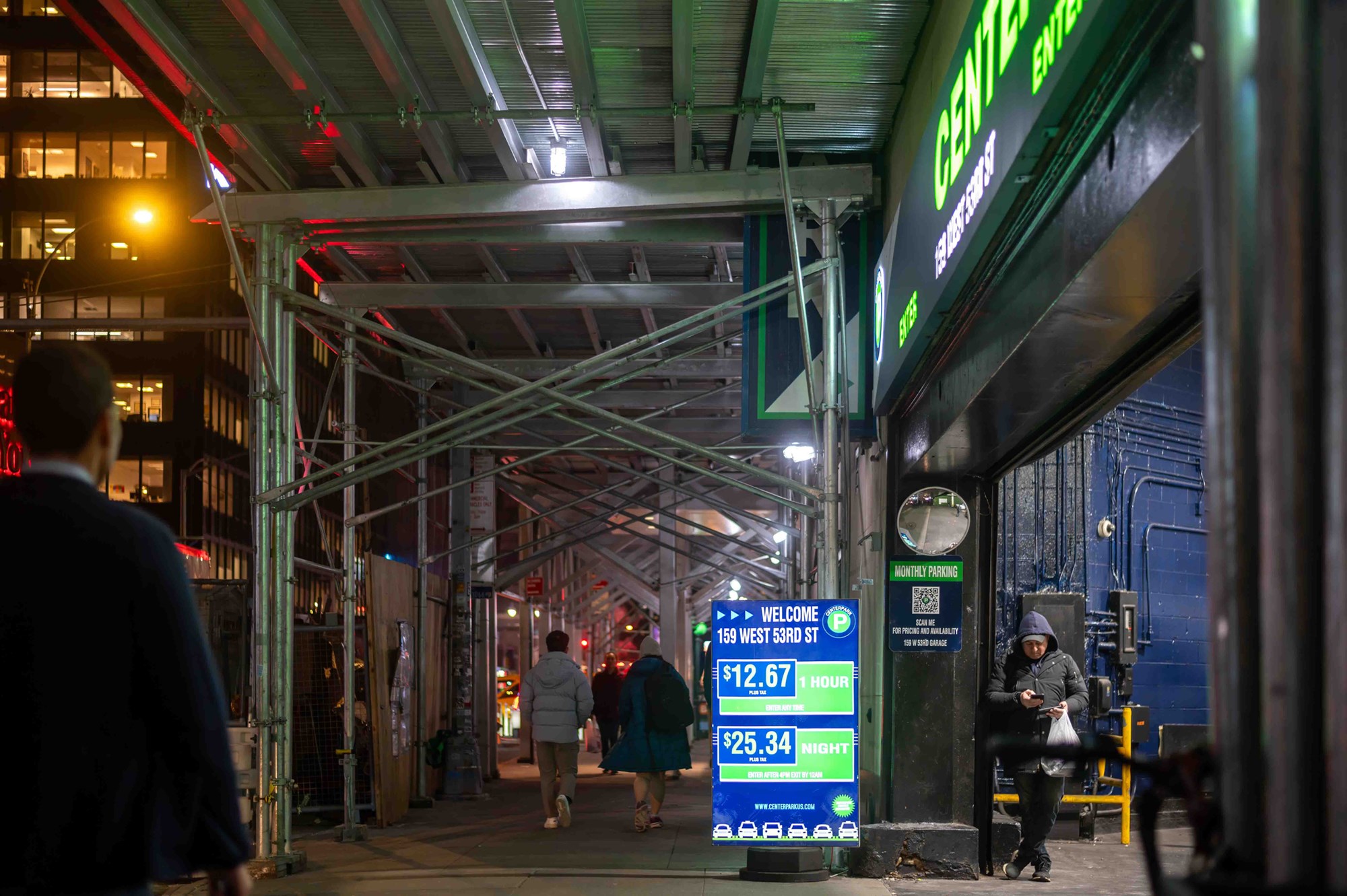 New York, NY, USA, 12-05-2023 New York City night time street scene with scaffolding parking garage entrance and pedestrians. Editorial use only.