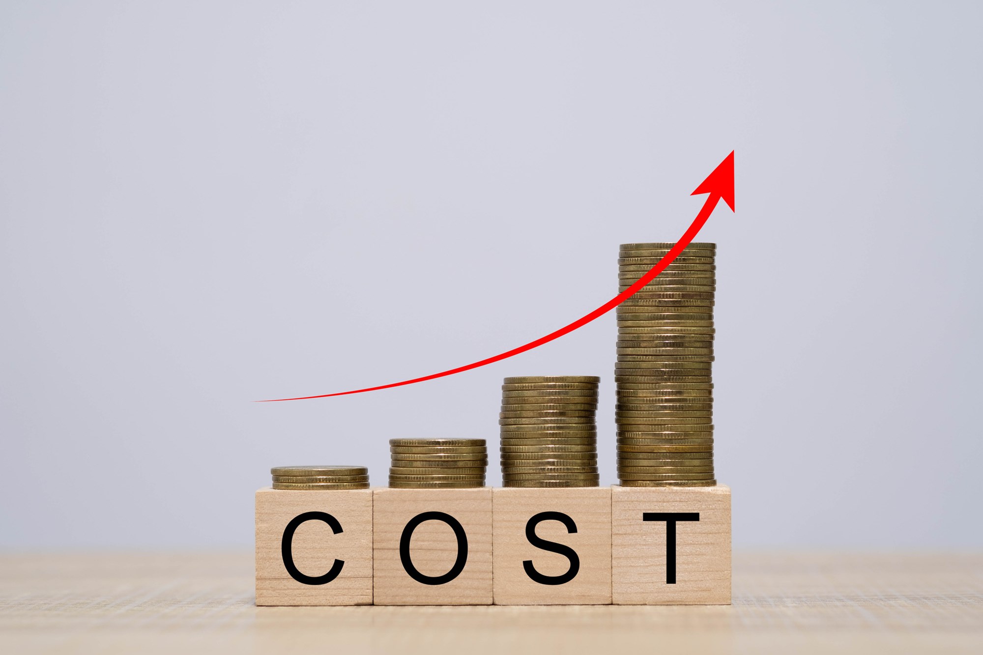 Stacks of coins increasing in height with a rising red arrow illustrate growing cost, financial pressure, inflation impact, business expenses, symbolizing economic challenges and budgeting concerns.